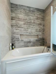 a white bath tub in a bathroom with a stone wall at Gems in Ratoath in Ratoath