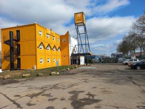 um edifício amarelo com uma placa ao lado de um parque de estacionamento em Premiere Classe Evry Sud - Mennecy em Ormoy