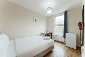 a white bedroom with a bed and a window at Mile End Rooms 57A in London