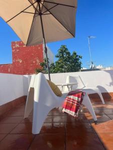 einen Tisch und Stühle mit Sonnenschirm auf einer Terrasse in der Unterkunft Apartamento Calvario in Rota