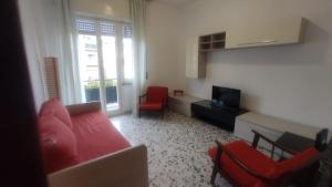 ein Wohnzimmer mit einem roten Sofa und Stühlen in der Unterkunft Lerici D'amare a 3 min a piedi dalla spiaggia in San Terenzo