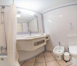 a bathroom with a sink and a toilet and a mirror at Apartamentos Solar do Sol in Albufeira