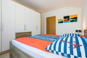 a bedroom with a bed with blue and white sheets at Apartments Sara in Milohnići