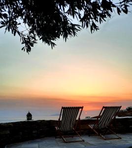 Agios Romanos的住宿－Aegean living Villa，日落时坐在大海前的两把椅子