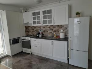 a kitchen with white cabinets and a sink and a refrigerator at Airplane Residence 1 in Otopeni +2 photos
