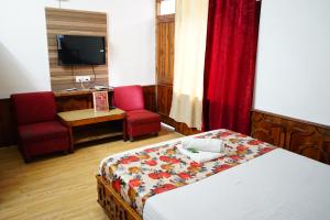 a hotel room with a bed and a chair and a desk at Hotel Magnolia Mallroad Manali in Manāli