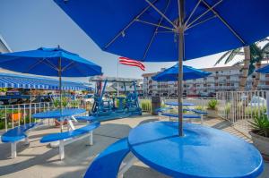 un groupe de tables bleues et de parasols sur un patio dans l'établissement Tangiers Resort Motel, à Wildwood Crest