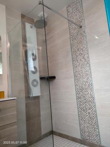 a shower with a glass door in a bathroom at Villa du Littoral in Mers-les-Bains