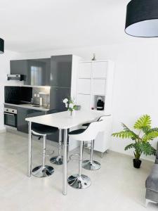 a white kitchen with a white table and stools at Maison 4 personnes avec jacuzzi in Marignane