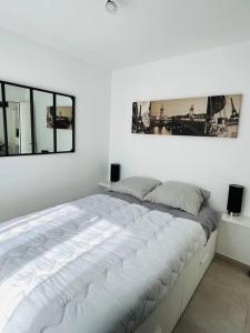 duże łóżko w białym pokoju z 2 oknami w obiekcie Maison 4 personnes avec jacuzzi w mieście Marignane