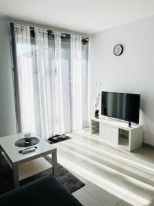 salon z telewizorem z płaskim ekranem i stołem w obiekcie Maison 4 personnes avec jacuzzi w mieście Marignane