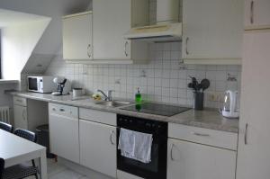 a kitchen with white cabinets and a black dishwasher at Gemütlich in St. Margarethen in Sankt Margarethen