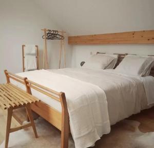 a bedroom with a large white bed and a wooden bench at Paulette à bicyclette, vue sur la rivière, Esneux in Méry