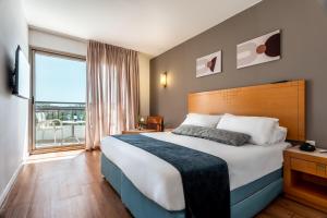 a hotel room with a bed and a large window at Jacob Eilat in Eilat