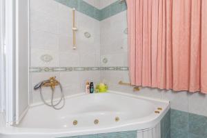 Doa - Apartment with Lovely Terrace & Sea View في مْليني: حوض استحمام أبيض في الحمام مع ستارة دش وردية اللون +19 صورة