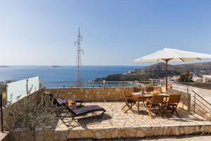 Doa - Apartment with Lovely Terrace & Sea View في مْليني: طاولة وكراسي مع مظلة والمحيط