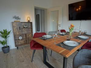 a dining room with a wooden table and red chairs at "HOGULU" Brandenburg, Balkon, Neustadt, Küche, Wassernähe - Parkplatz inklusive in Brandenburg an der Havel