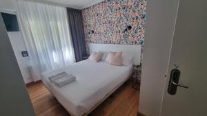 1 dormitorio con cama blanca y papel pintado con motivos florales en Hotel Norte, en Zarautz