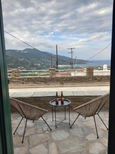 un patio con 2 sillas y una mesa con botellas. en Aurora Andros House, en Korthi