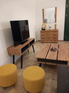 a living room with a tv and two yellow stools at Aurora Andros House in Korthi