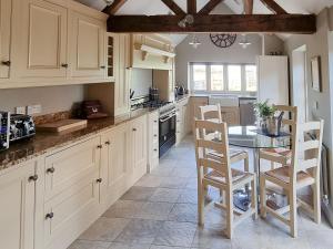 a kitchen with white cabinets and a table and chairs at The Creamery in Alrewas