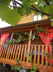 uma casa com um alpendre em madeira com cortinas vermelhas em Семейный домик под ключ у моря в Новом Афоне! em Novy Afon
