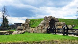 a stone building on a grassy hill with a fence at Domek Hobbita z jaskinią SPA - Osada Jaworzyny in Tokarnia +29 photos