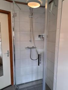 een badkamer met een douche en een glazen deur bij Onder de Boomen in Bergen