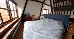 een slaapkamer met een bed in een kamer met ramen bij Onder de Boomen in Bergen