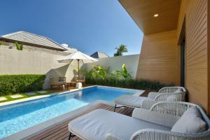an outdoor patio with a swimming pool and chairs at The Claremont Luxury Villas in Seminyak