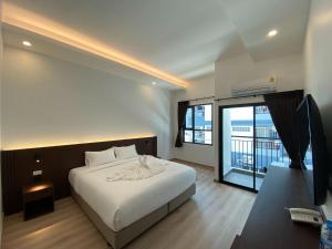 1 dormitorio con cama blanca y balcón en GEEN Hotel Chonburi, en Chonburi