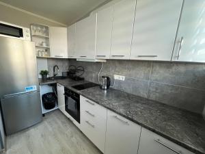 a kitchen with white cabinets and stainless steel appliances at RONY apartment in Liepāja