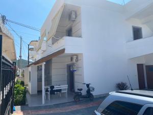 ein weißes Gebäude mit einem Tisch und einem daneben geparkten Motorrad in der Unterkunft Vila Avni Likometi in Ksamil