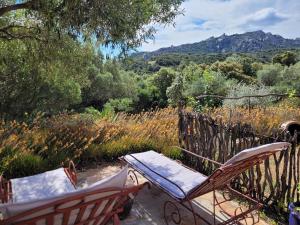 a couple of chairs sitting on a patio with mountains in the background at Stazzu la Capretta Farm Camping & Guest Rooms in Olbia