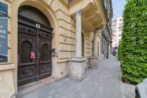 un edificio con una grande porta in legno su una strada di Downtown Heart 3bdr Jokai square AC a Budapest