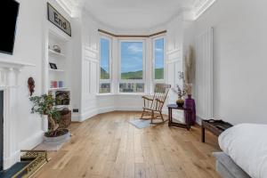 a white room with a bed and a chair and windows at spacious flat, close to the city centre with scenic views in Edinburgh