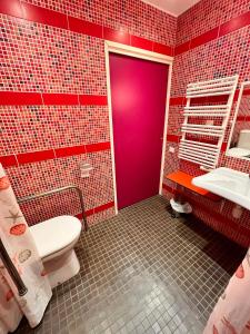 uma casa de banho vermelha com um WC e uma porta roxa em La ferme du paradis em Merris