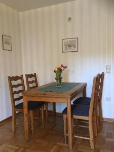 una mesa de comedor con un jarrón de flores. en Waldgasthof Röckers-Ferienwohnung Hahnenkrai, en Meppen