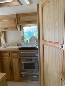 a kitchen with a stove and a sink in an rv at Delightful Beach & Forest Caravan in Chernomorets