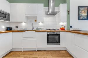 a white kitchen with wooden floors and white cabinets at spacious flat, close to the city centre with scenic views in Edinburgh