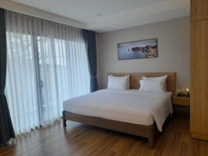 um quarto com uma cama com lençóis brancos e janelas em Happy Home em Nha Trang