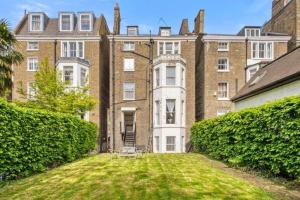 un grand bâtiment avec une pelouse devant lui dans l'établissement Charming Apartment Earls Court, à Londres