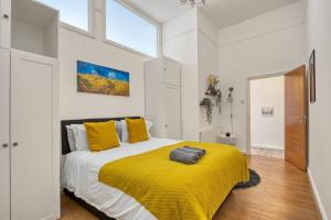 - une chambre avec un grand lit et une couverture jaune dans l'établissement Charming Apartment Earls Court, à Londres