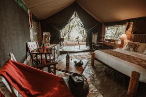 um quarto com uma cama e uma secretária numa tenda em Mara Olapa Camp em Lolgorien