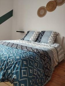 a bedroom with a bed with a blue and white comforter at Appartement Foch in Le Puy en Velay