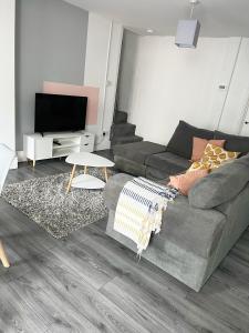 ein Wohnzimmer mit einem Sofa und einem TV in der Unterkunft Cozy Cribs near Zipworld, Dare Valley Bike Park, Pen-y-fan & Four Waterfalls Walk in Aberdare