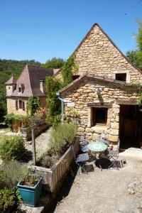 una casa de piedra con una mesa delante en La Maison Bleue - Gîte de Charme en Périgord en Vitrac