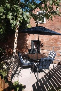 Una mesa y sillas bajo una sombrilla en un patio. en The Gardener's Cottage, en Leominster