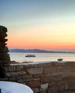 a boat on the water with the sunset in the background at Aegean living Villa in Agios Romanos