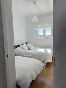 2 camas en una habitación blanca con ventana en Villa Mariaje, en Cazalla de la Sierra